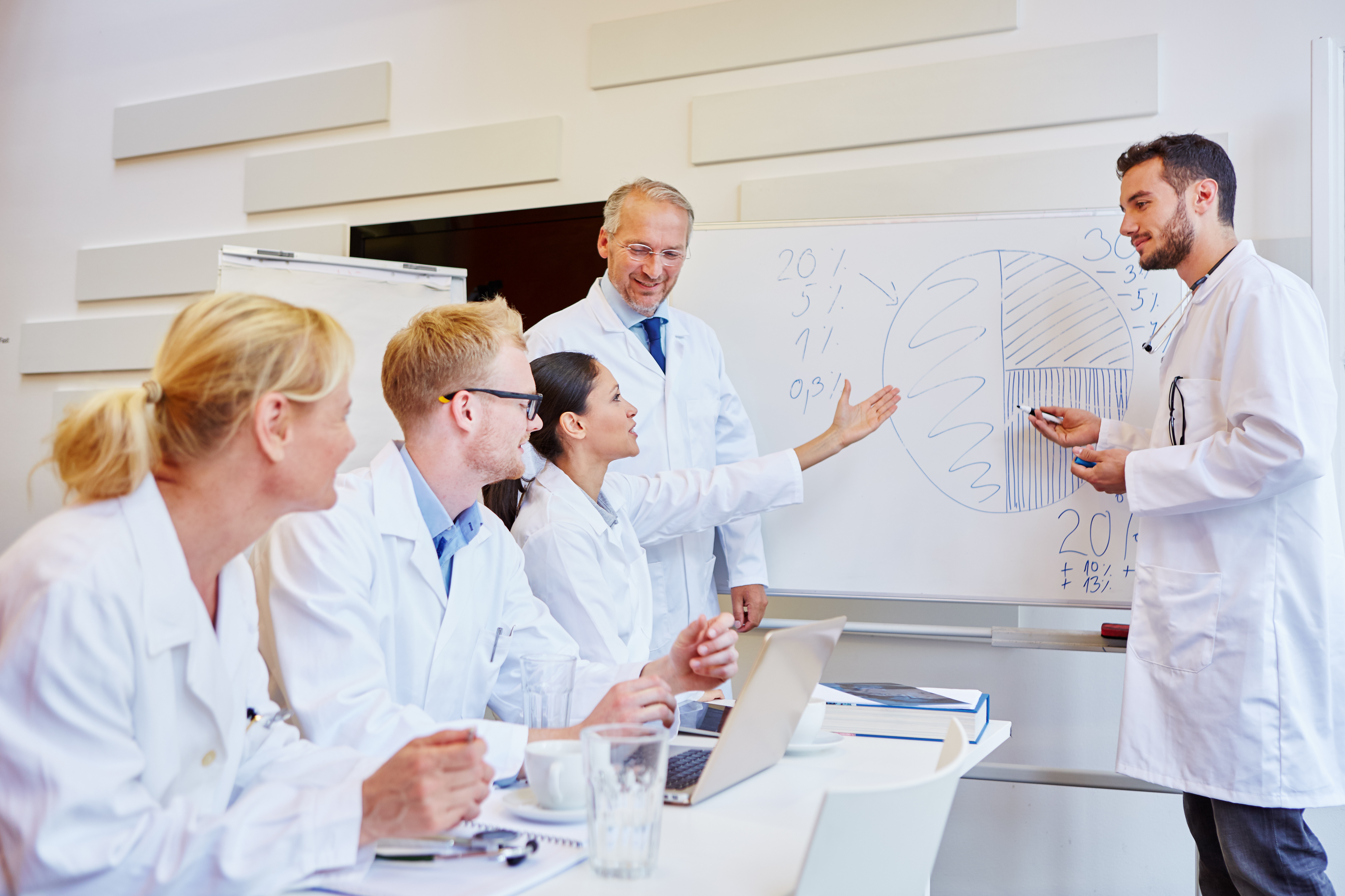 medical professionals huddled around a white board discussing